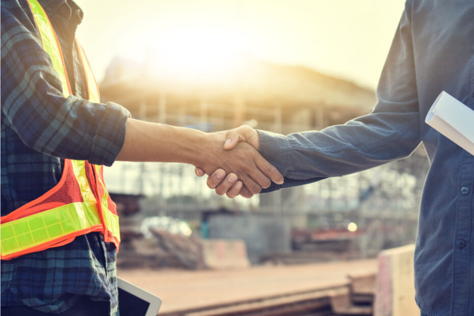 Handschlag zwischen Bauleiter in Warnweste und Auftraggeber auf einer Baustelle